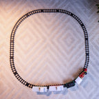 A train track set arranged in a large oval on a light beige patterned rug, with a red and black train pulling white passenger cars.