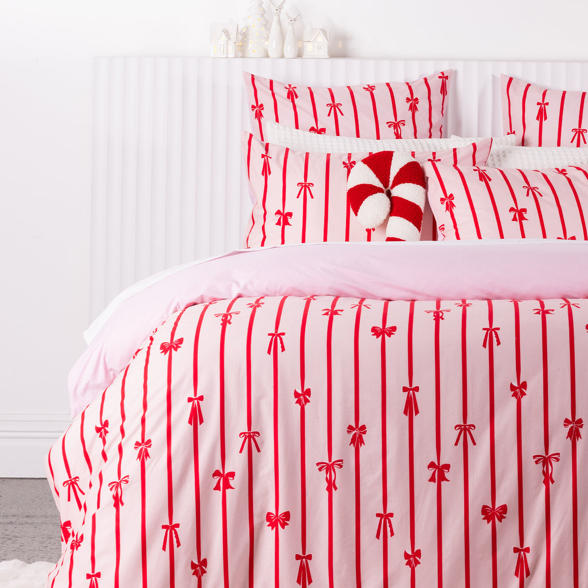 Close-up of the Christmas Wishes Bows Duvet Cover Set, showcasing the red bow and stripe design with a plain pink reverse and matching pillowcases.