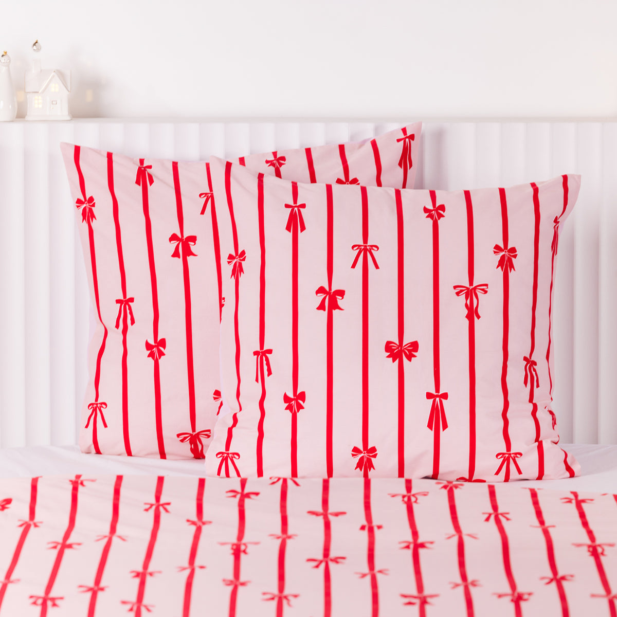 Christmas Wishes Bows Euro Pillowcase Pair in pink with red vertical stripes and bow detailing, styled on a bed with matching bedding.
