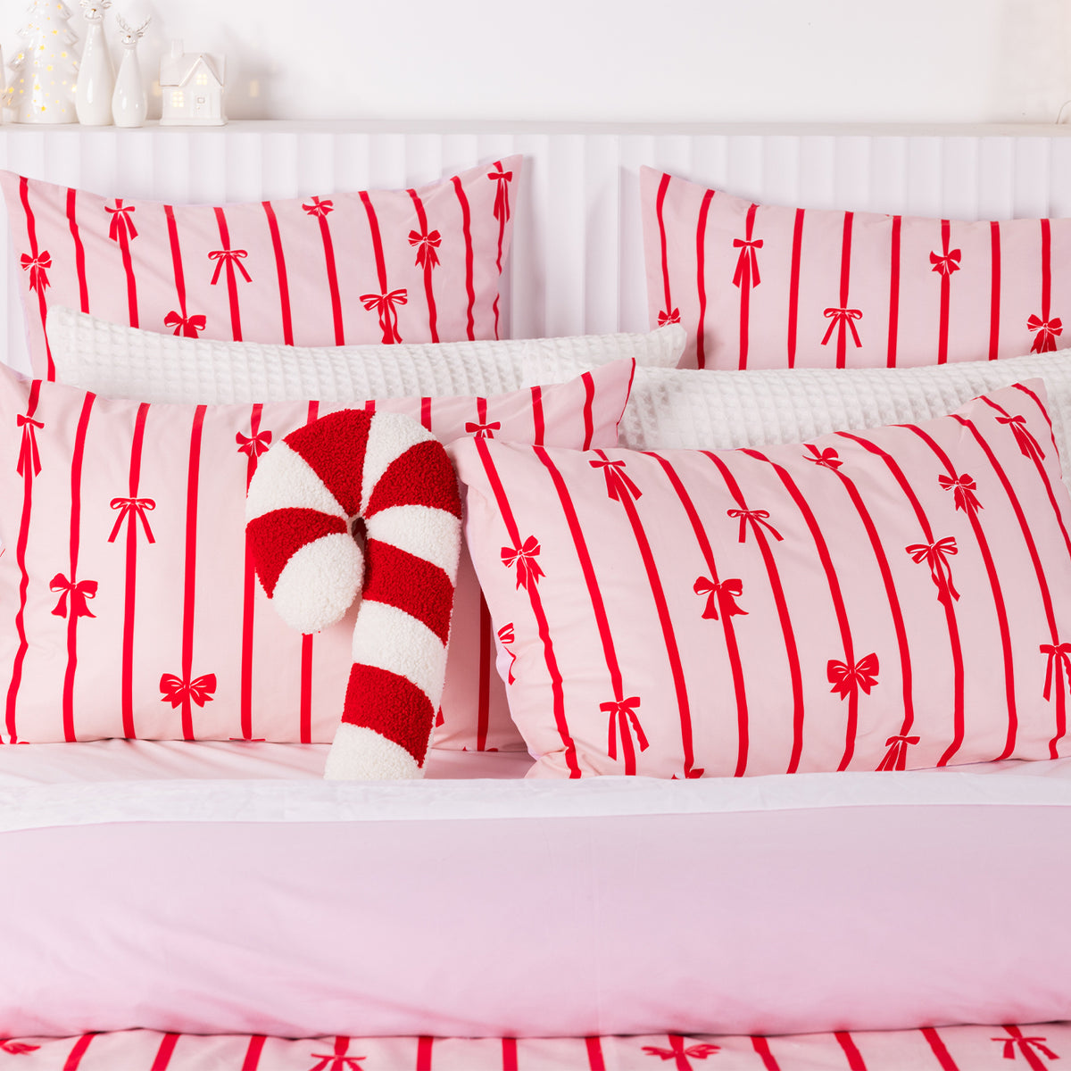 Christmas Wishes Bows Euro Pillowcases styled with matching cushions, white textured pillows and a red and white candy cane cushion.