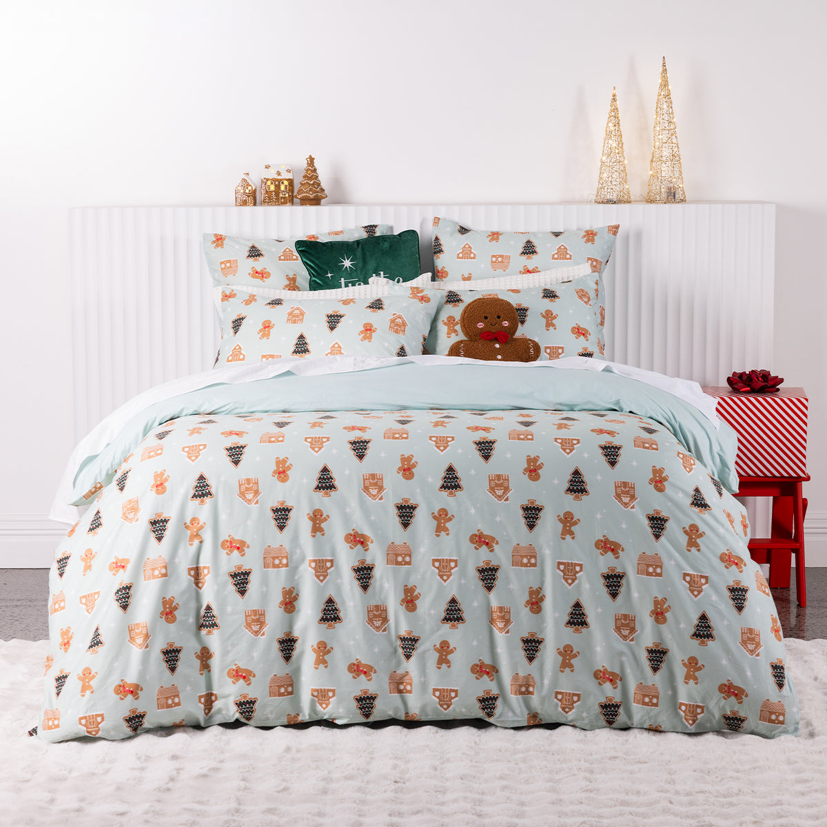 Christmas Wishes Sugar Spruce Duvet Cover Set featuring festive gingerbread men, Christmas trees and gingerbread houses on a pale mint background, styled on a bed with Christmas decorations.