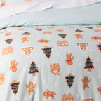 Close-up of the Sugar Spruce Duvet Cover featuring gingerbread men, Christmas trees and gingerbread houses on a pale mint background.