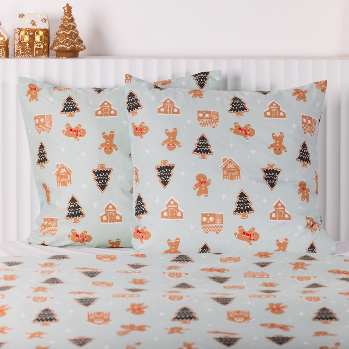 Christmas Wishes Sugar Spruce Euro Pillowcase Pair featuring gingerbread men, Christmas trees and gingerbread houses on a pale mint background, styled with matching bedding.