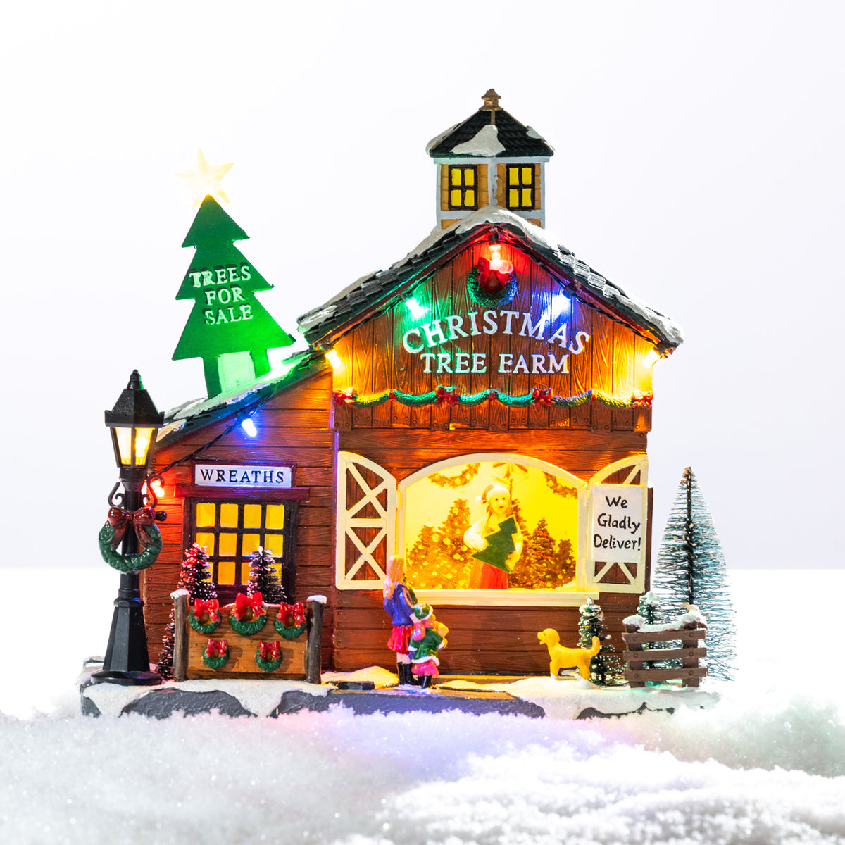 A whimsical illuminated Christmas tree farm featuring a snowy barn, colourful lights, festive wreaths and tiny shoppers choosing their perfect tree.