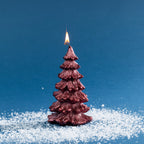 Decorative Christmas tree-shaped candle in a deep metallic red finish, featuring layered textured branches and a lit wick.