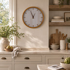 A natural timber-framed wall clock with a softly whitewashed face adds warm, modern farmhouse style to a bright, thoughtfully styled kitchen.