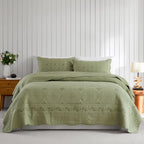 Green coverlet set styled on a bed with matching pillows in a neutral bedroom.