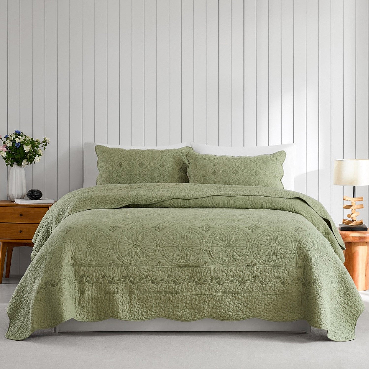 Green coverlet set styled on a bed with matching pillows in a neutral bedroom.