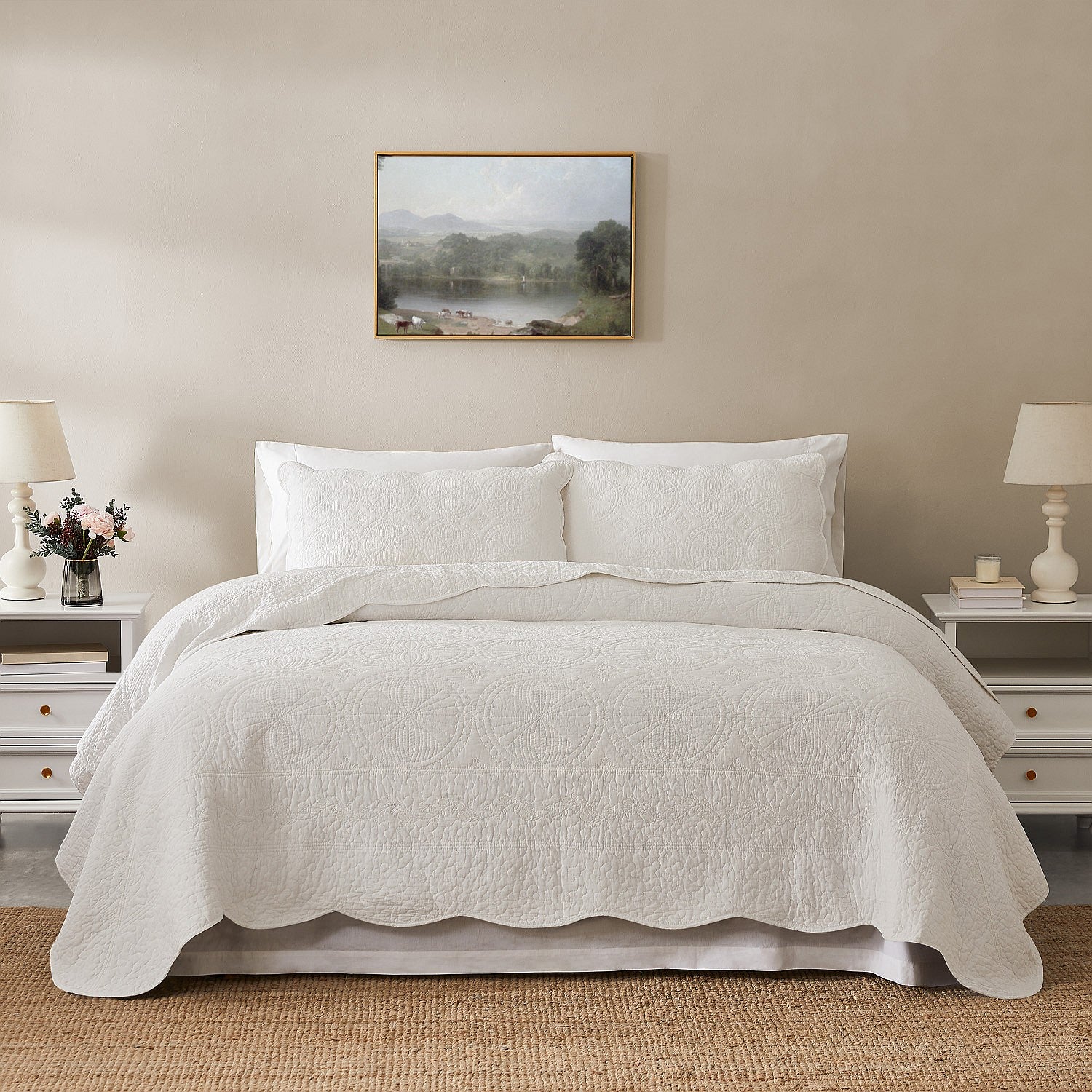 White coverlet set styled on a bed with matching pillows in a neutral bedroom.