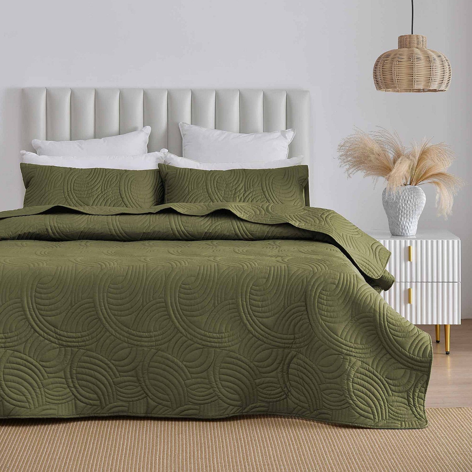 Olive green quilted coverlet set styled on a bed in a neutral bedroom.