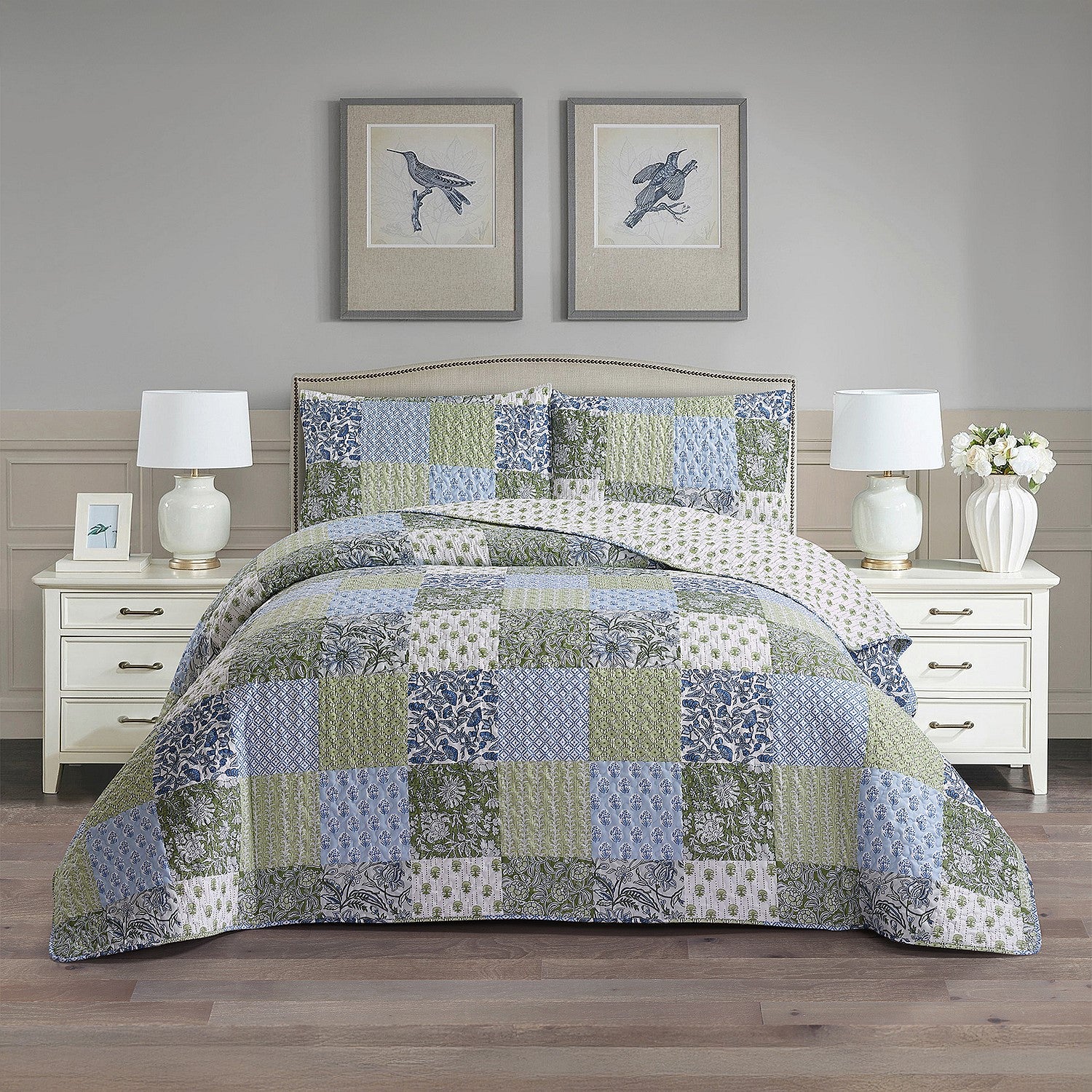 Patchwork coverlet set in blue, green and grey tones styled on a bed with matching pillowcases in a neutral bedroom.