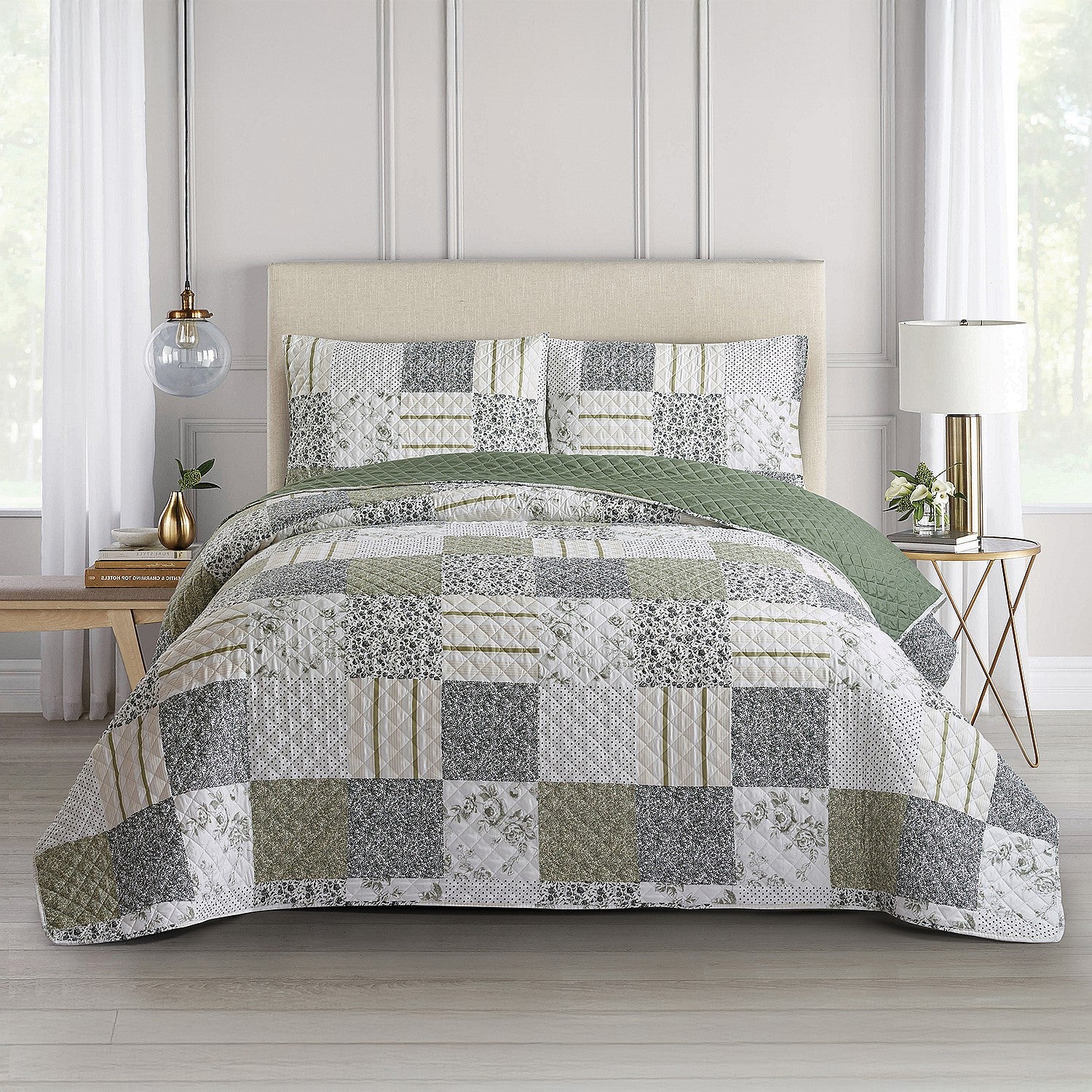 Green, grey and cream patchwork coverlet set styled on a bed with matching pillowcases in a bright bedroom.