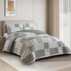 Green, grey and cream patchwork coverlet set styled on a bed with matching pillowcases in a bright bedroom.