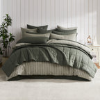 Thyme coverlet set styled on a bed with matching pillows with a striped green duvet cover underneath in a neutral bedroom.