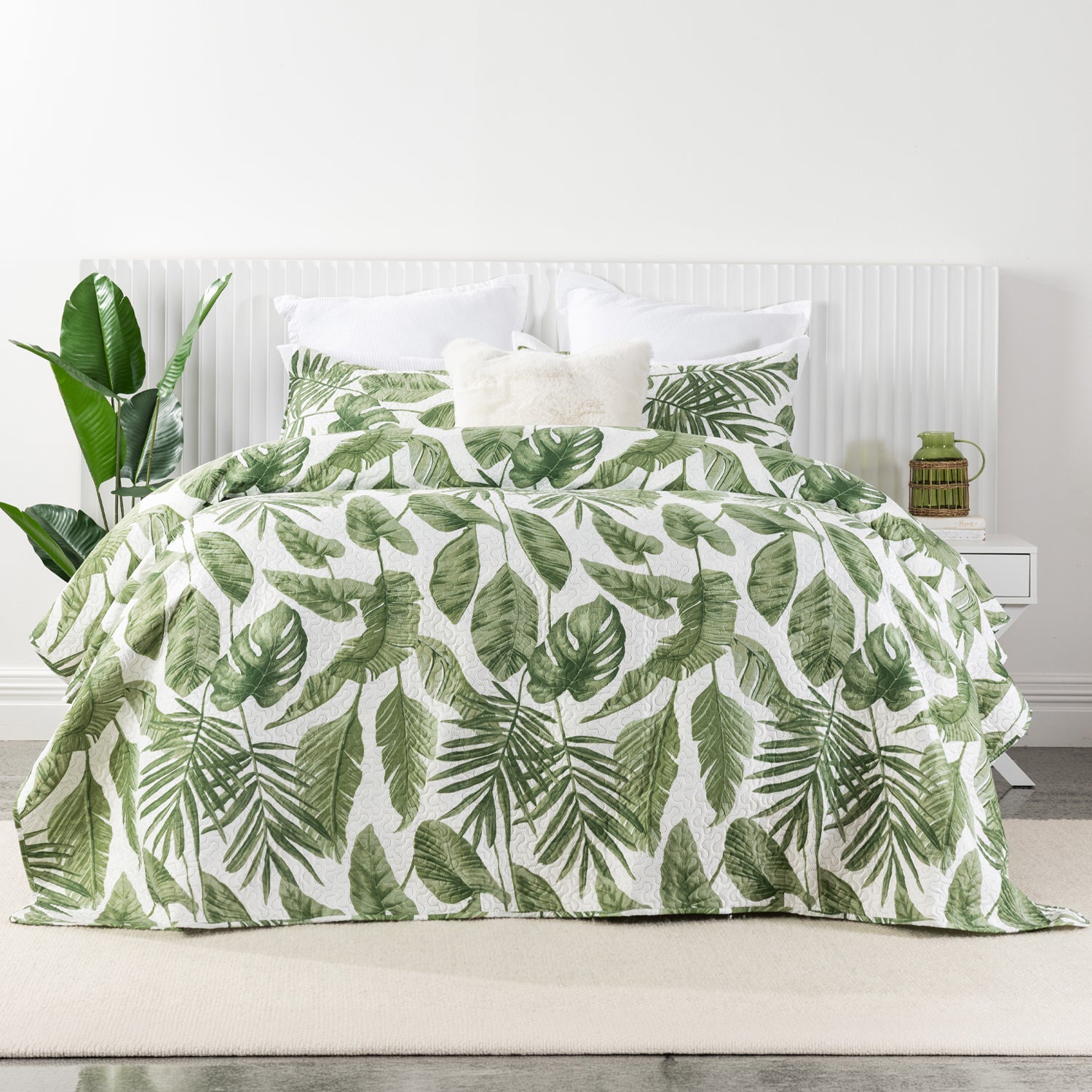 A fresh tropical leaf print quilt coverlet set in vibrant green tones brings a lush, botanical feel to this bright, contemporary bedroom.