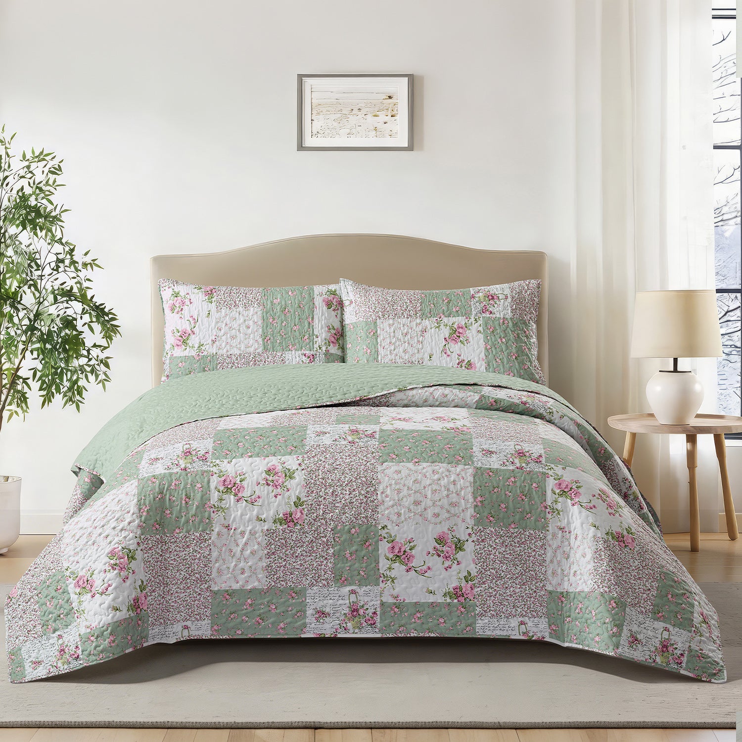 A patchwork quilted bedding set with floral and textured square patterns in sage green, dusty pink, and white, styled on a beige bed frame in a bright, modern bedroom.
