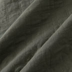 Close-up of the olive green quilted fabric showing the stitched grid and floral detailing.