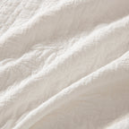 Close-up of the soft white quilted fabric showing the raised floral stitching and textured finish.