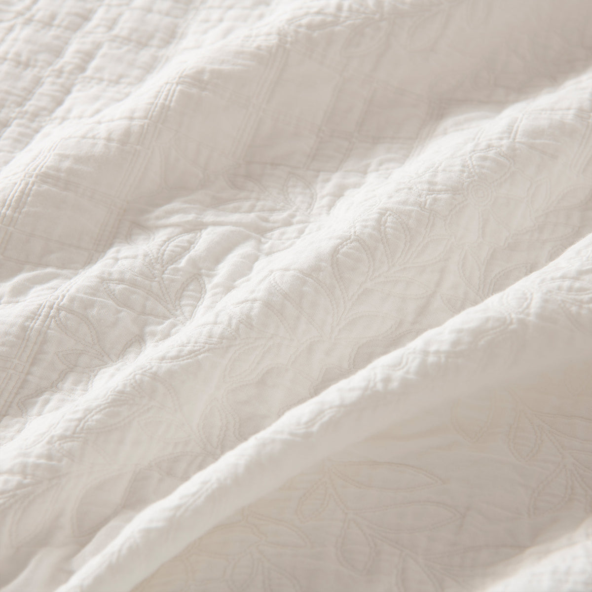 Close-up of the soft white quilted fabric showing the raised floral stitching and textured finish.