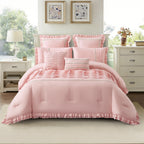 Dusty pink comforter set styled on a bed featuring pleated detailing, decorative trim accents, ruffled edges, and coordinating cushions in a bright bedroom setting.