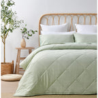 Light green quilted coverlet set styled on a bed in a bright neutral bedroom.