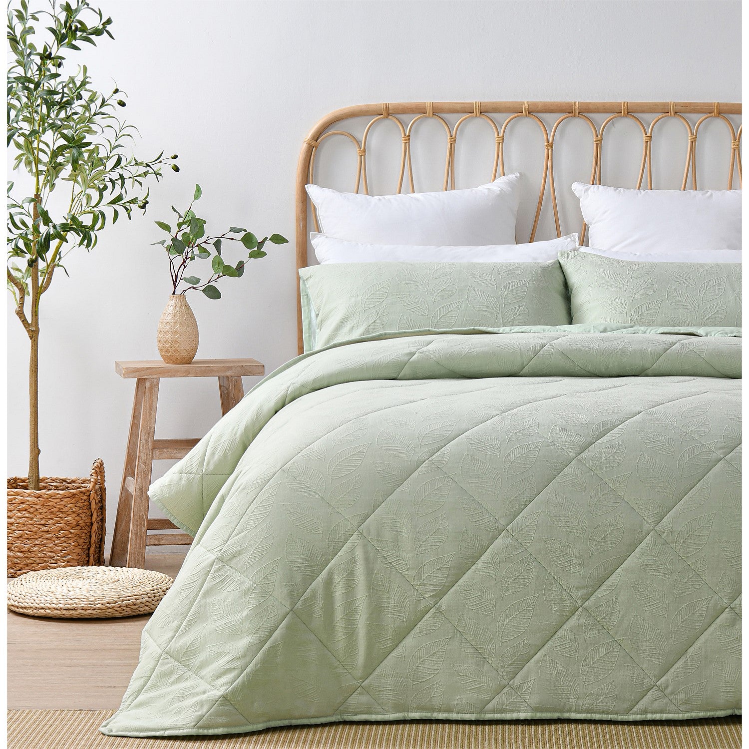 Light green quilted coverlet set styled on a bed in a bright neutral bedroom.