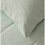 Light green quilted coverlet close-up showing soft textured fabric and stitched detail and matching pillowcase