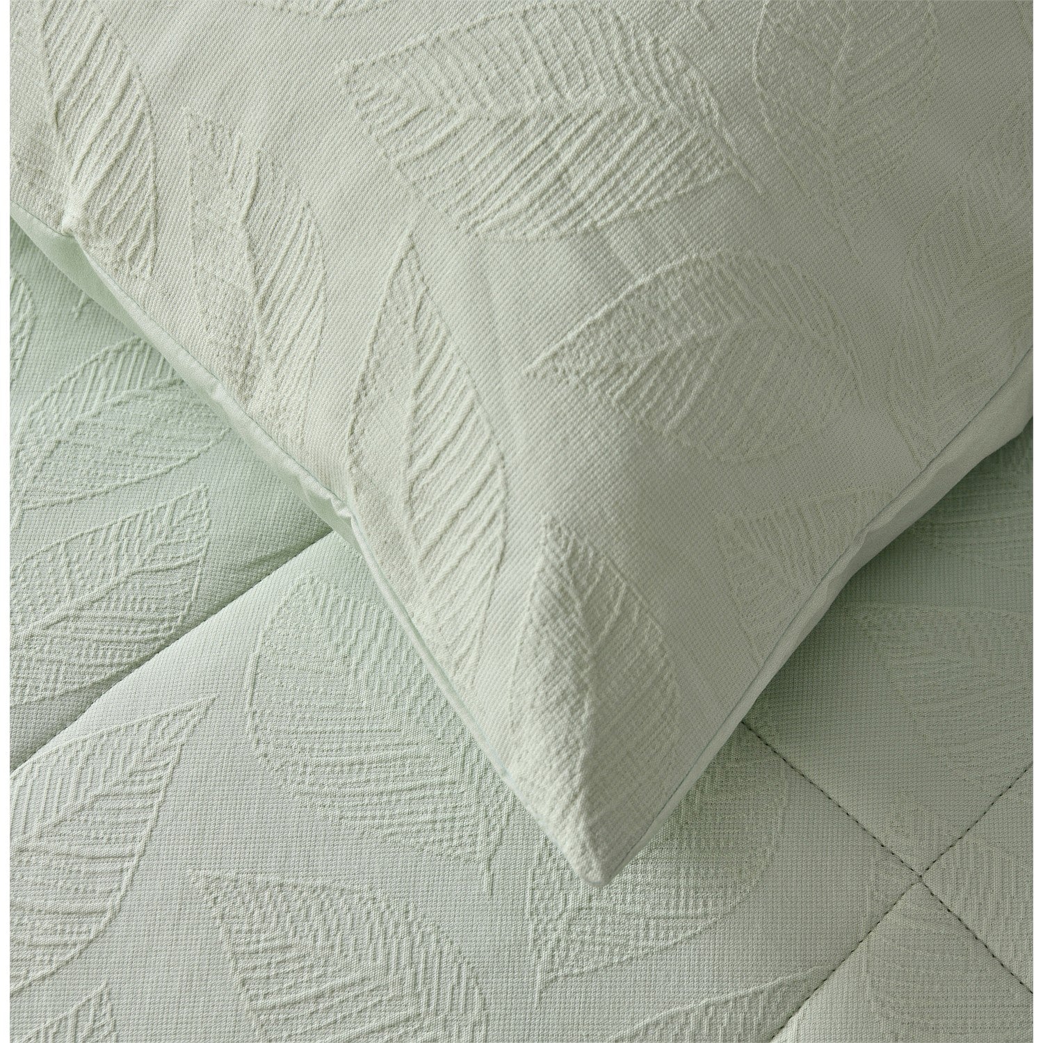 Light green quilted coverlet close-up showing soft textured fabric and stitched detail and matching pillowcase
