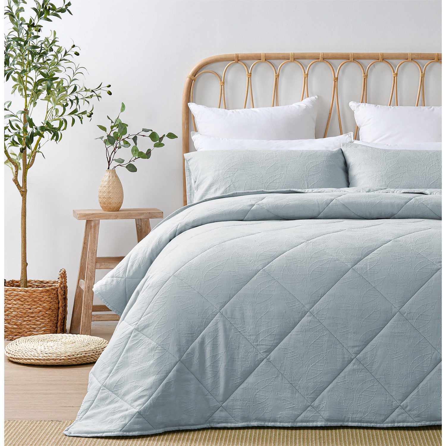 Light blue quilted coverlet set styled on a bed in a bright neutral bedroom.
