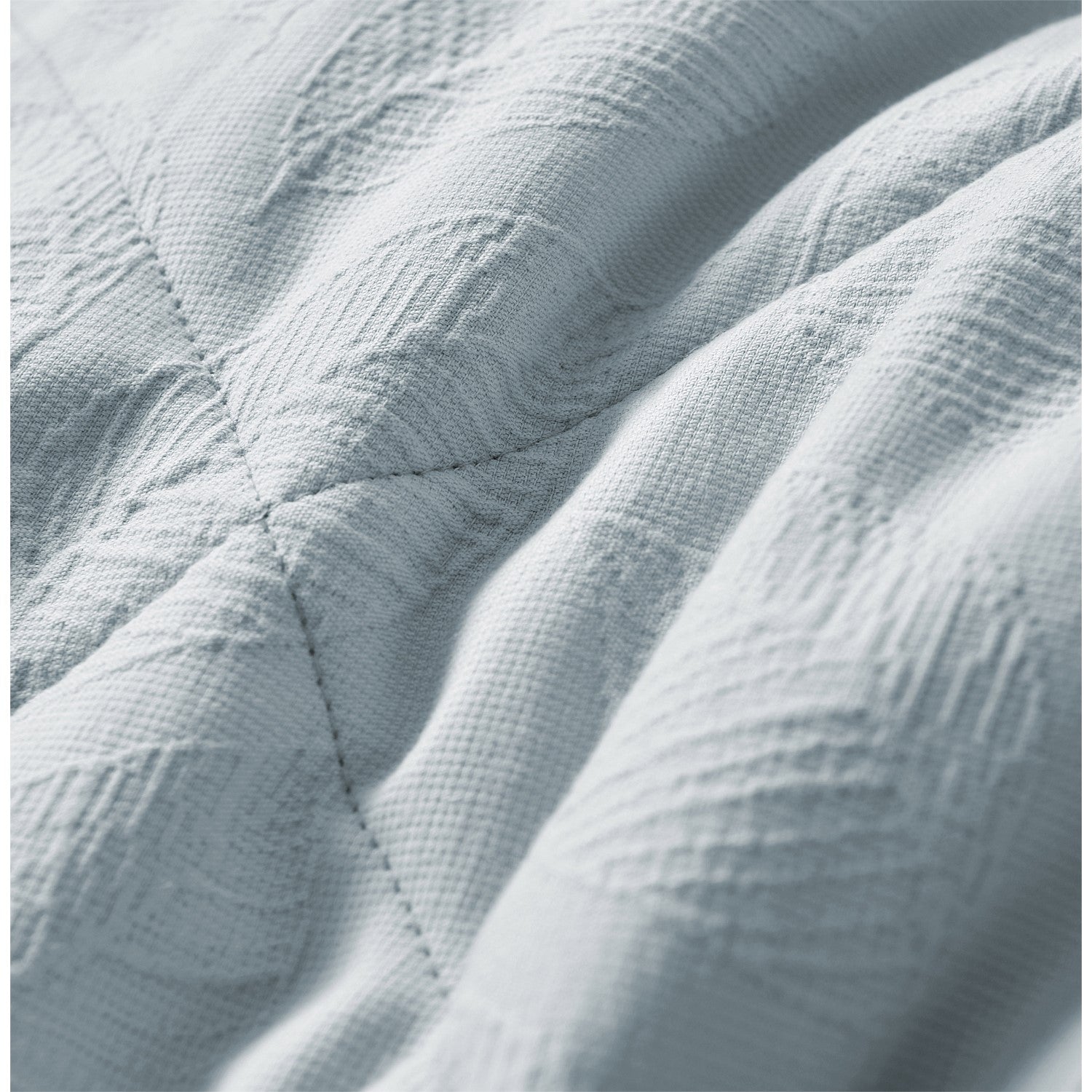 Light blue quilted coverlet close-up showing soft textured fabric and stitched detail.