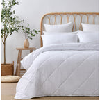 White quilted coverlet set styled on a bed in a bright neutral bedroom.