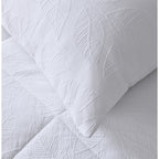 White quilted coverlet close-up showing soft textured fabric and stitched detail and matching pillowcase