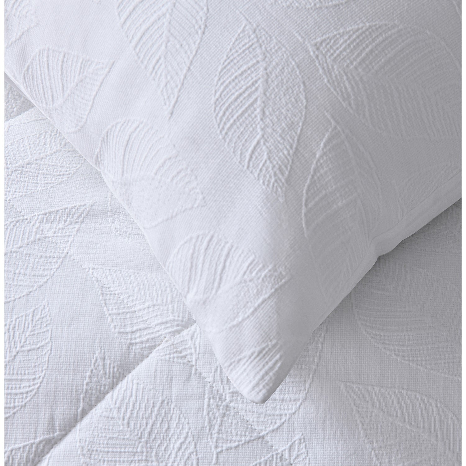 White quilted coverlet close-up showing soft textured fabric and stitched detail and matching pillowcase