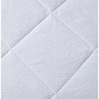 White quilted coverlet close-up showing soft textured fabric and stitched detail