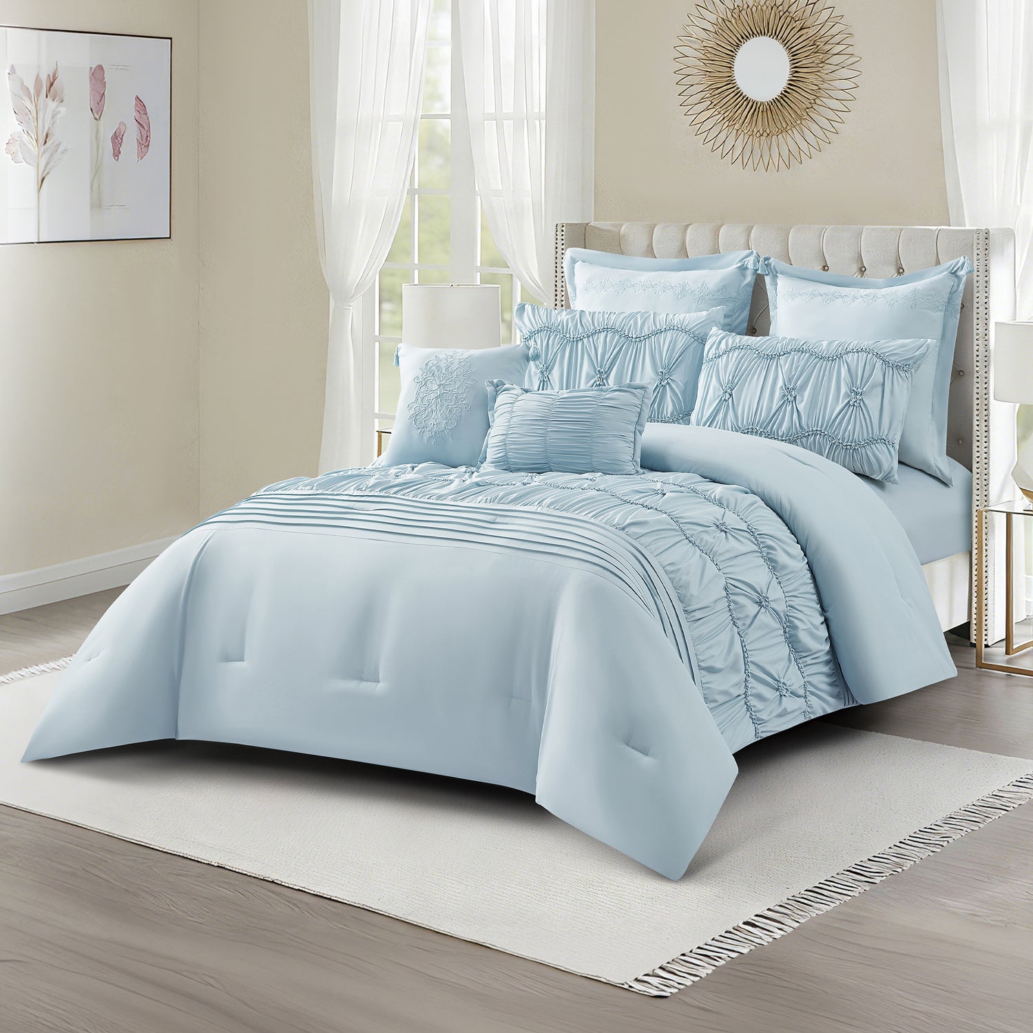 Angled view of a cornflower blue comforter set with gathered panels, textured ruching, pleated detailing, and matching decorative cushions, styled in a light and airy bedroom.
