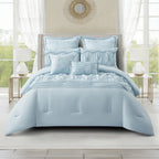 Cornflower blue comforter set styled on a bed featuring gathered detailing, decorative ruching, pleated accents, and coordinating cushions in a bright, elegant bedroom setting.