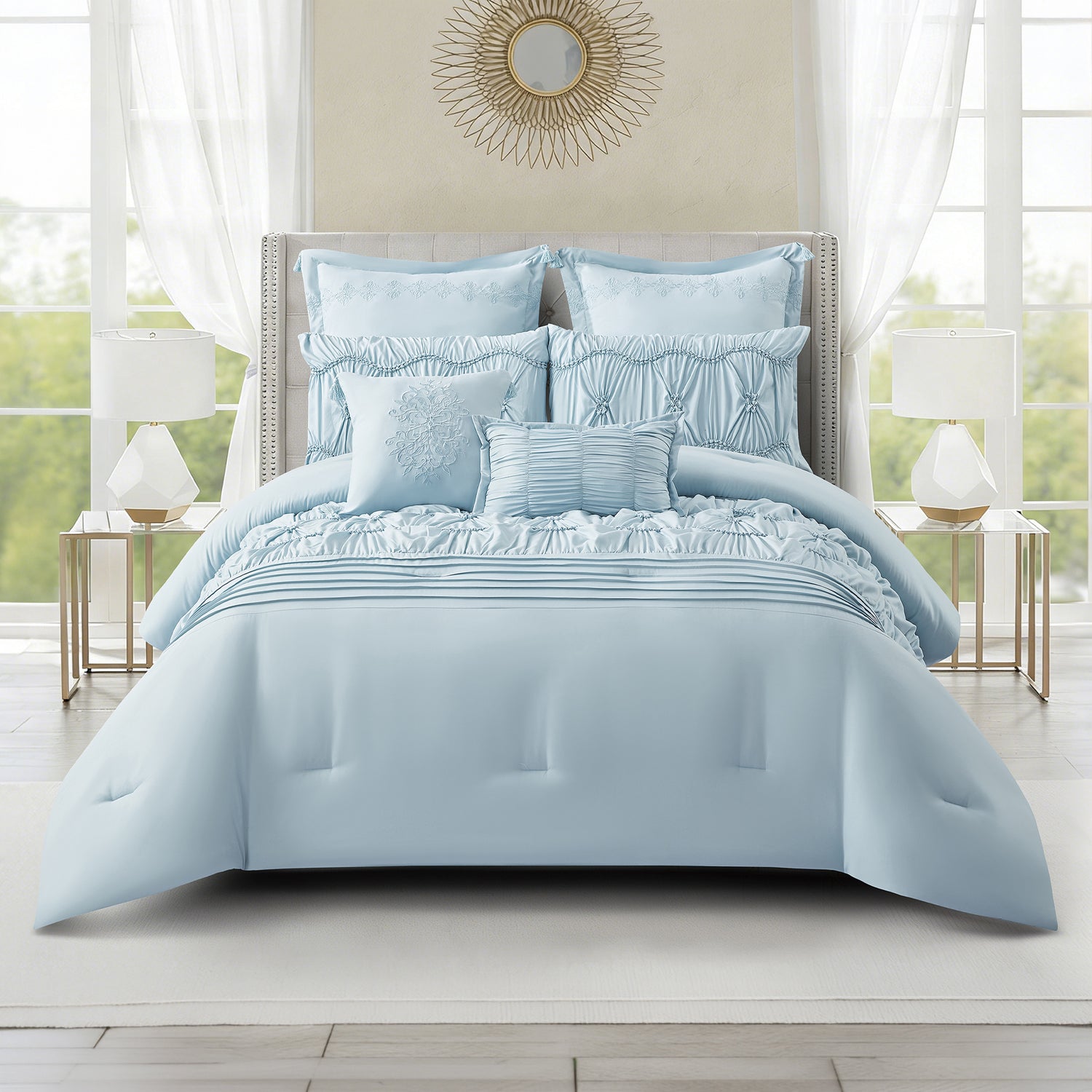 Cornflower blue comforter set styled on a bed featuring gathered detailing, decorative ruching, pleated accents, and coordinating cushions in a bright, elegant bedroom setting.
