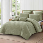 Angled view of the sage green textured 7-piece comforter set with coordinating pillows and cushions on a wooden bed in a light-filled bedroom.