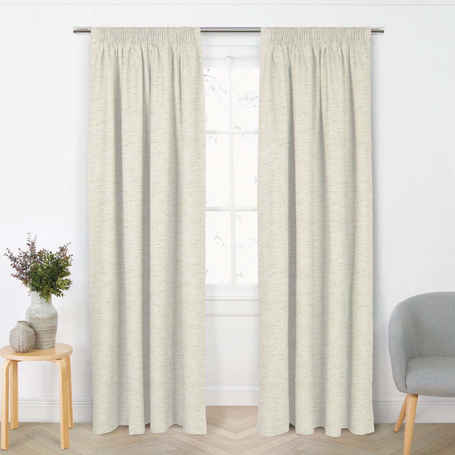 Pair of natural blockout ready-made curtains with a subtle textured weave hanging from a silver curtain rod in a bright living room.