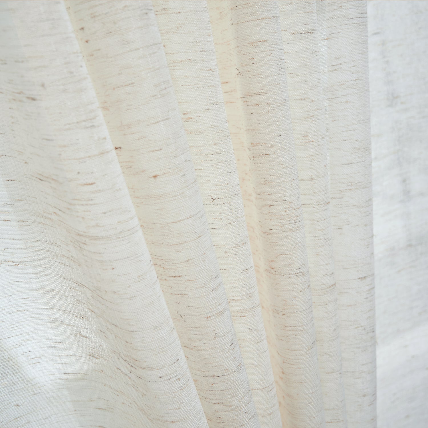 A close-up of an linen sheer curtain showcases its softly textured woven fabric and elegant drape as it gently filters natural light.