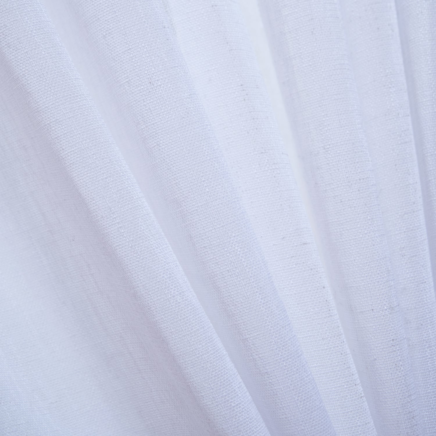 A close-up of a white sheer curtain highlights its finely woven texture and soft, flowing drape as it gently filters natural light.
