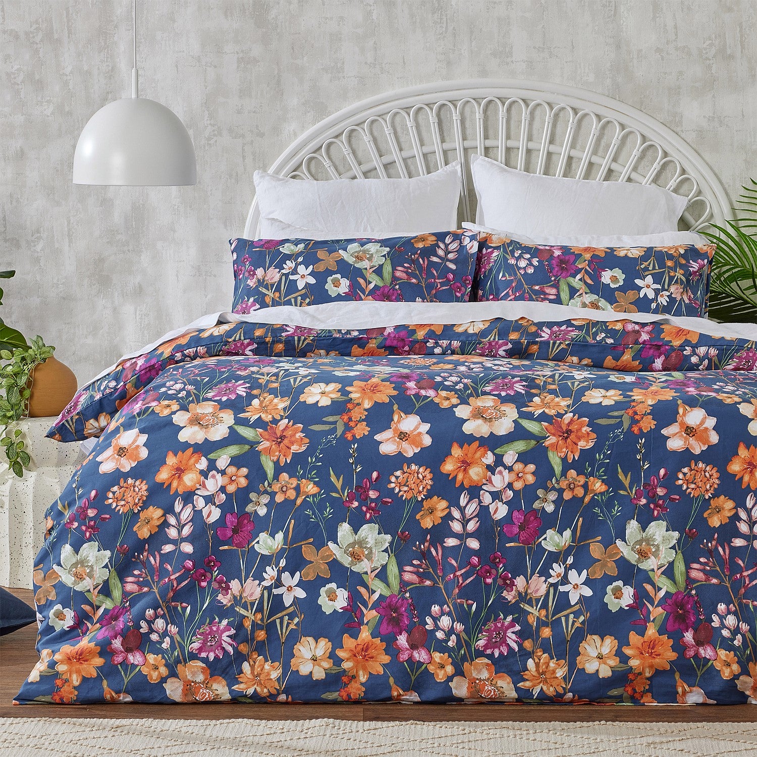 Floral bedding set on a bed with a white headboard and gray wall.