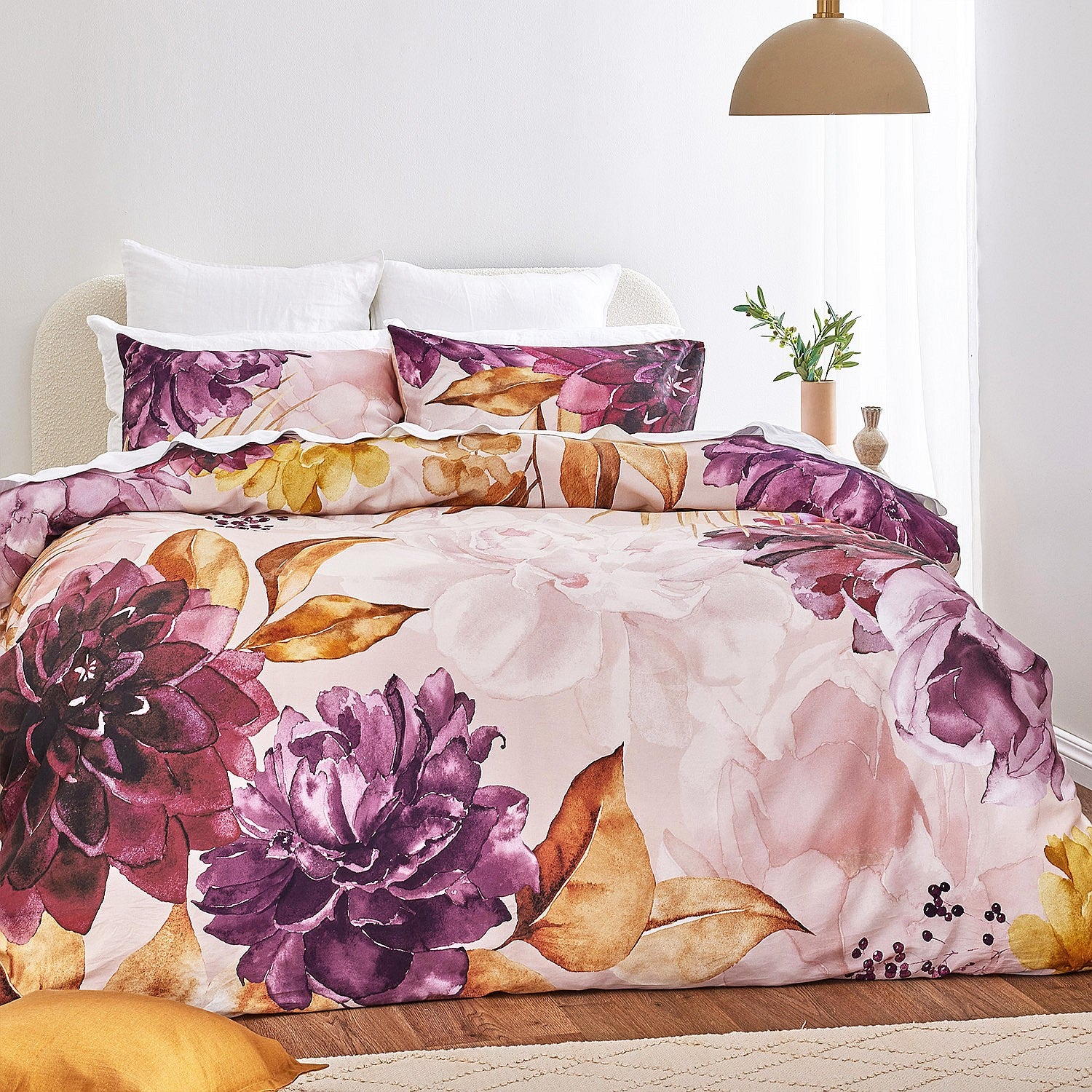 Floral bedding set with purple and pink flowers on a bed in a bedroom.