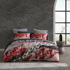 Bed with red and gray patterned bedding in a room with a textured wall and large window.