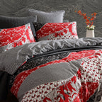 Bedding set with red, black, and gray patterned comforter and pillows against a textured wall.