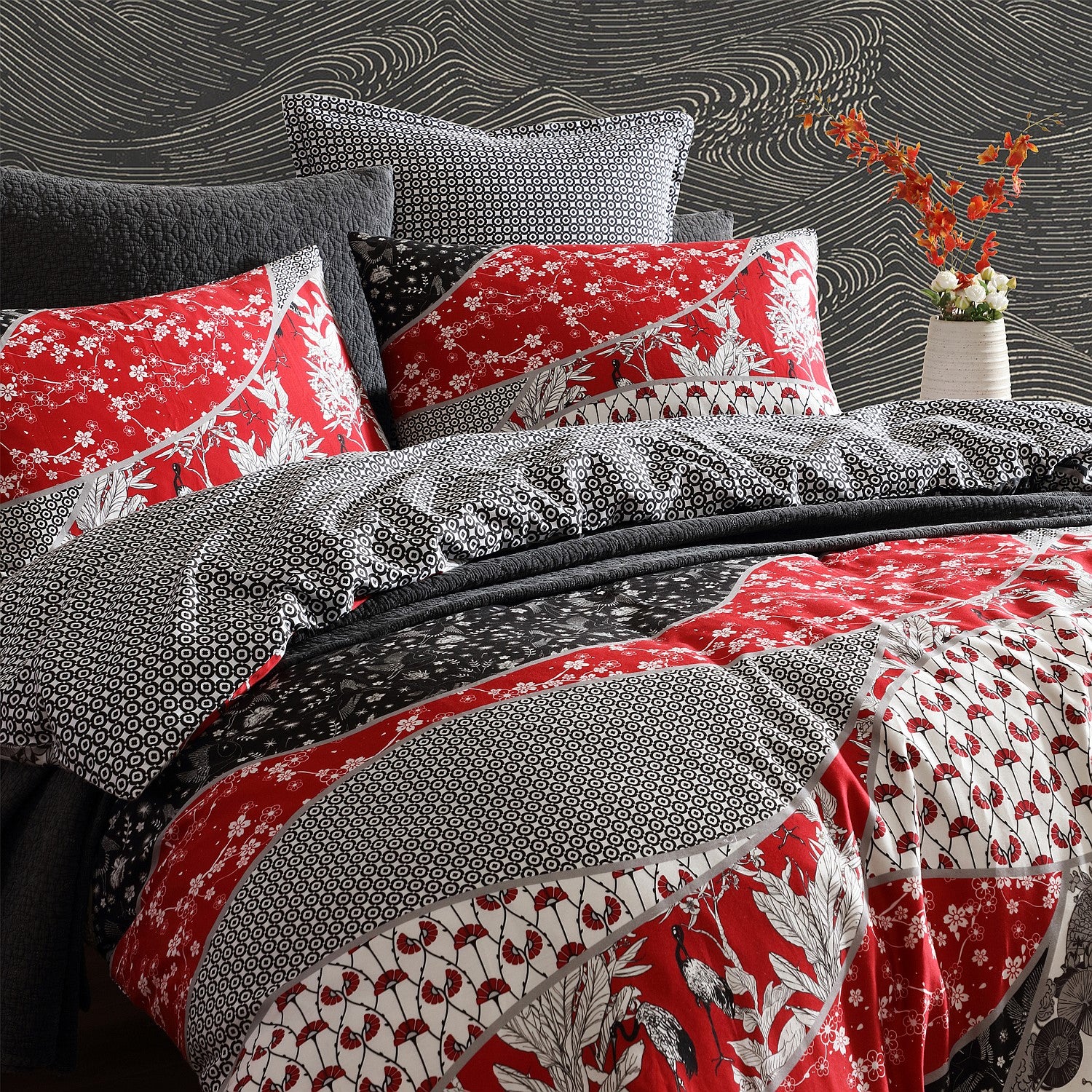 Bedding set with red, black, and gray patterned comforter and pillows against a textured wall.