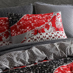 Patterned pillows and bedding with red, black, and white designs on a bed.