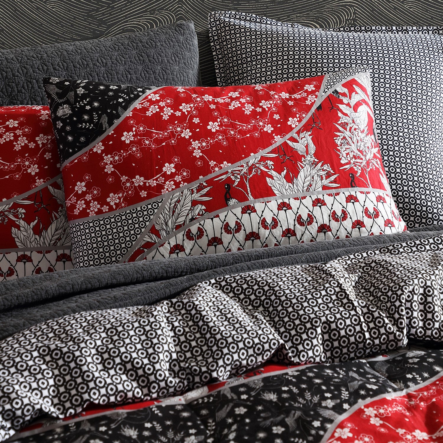 Patterned pillows and bedding with red, black, and white designs on a bed.