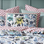 Floral patterned bedding set with decorative pillows on a bed.