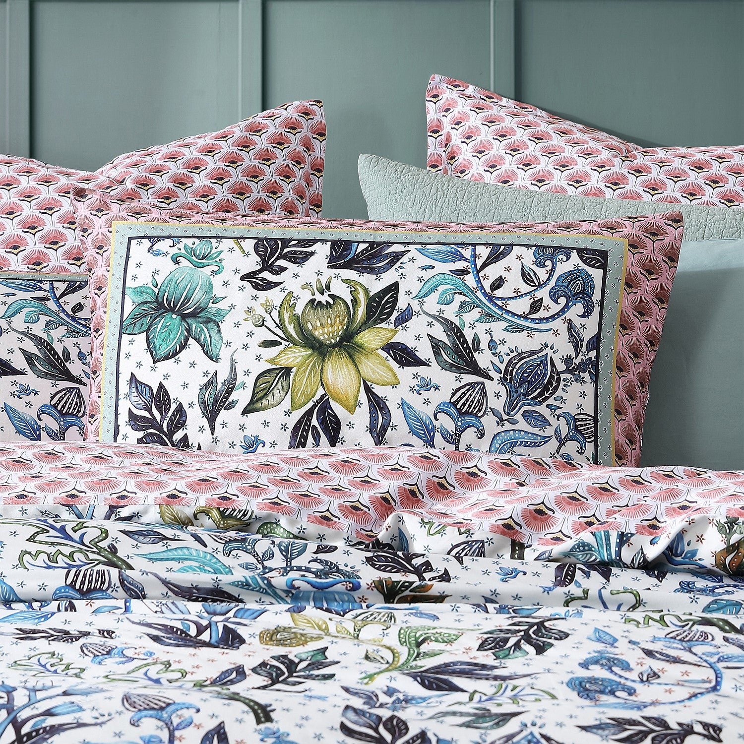 Floral patterned bedding set with decorative pillows on a bed.